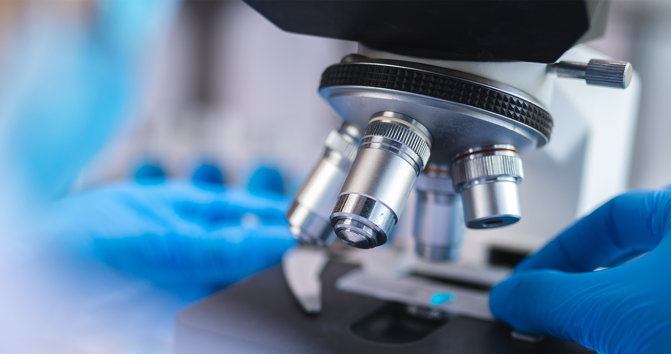 A researcher adjusting a laboratory microscope.